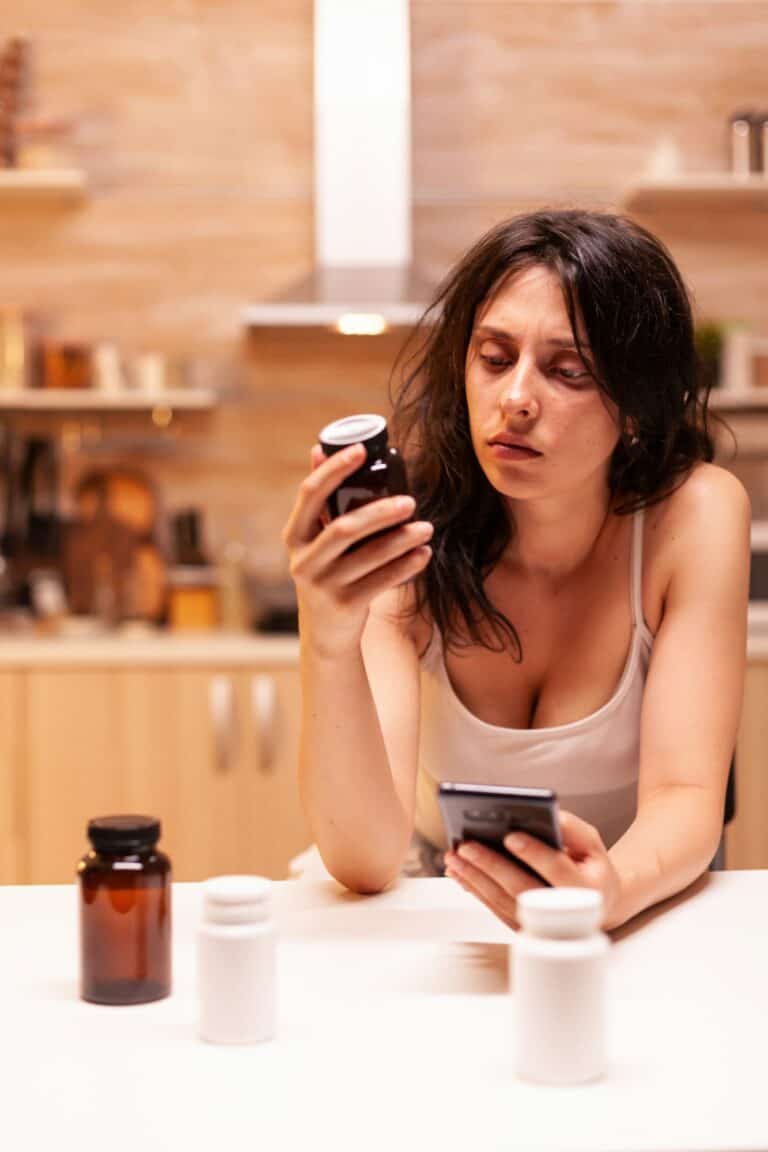 Unhealthy woman looking at pills bottle