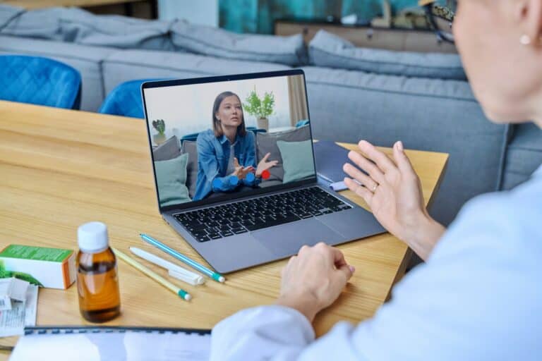 Young woman in laptop screen having video online counseling with female doctor